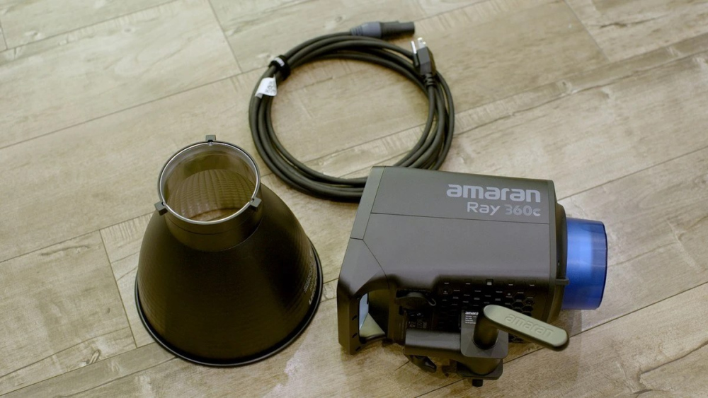 Моноблок Amaran Ray 360c з кришкою Bowens, рефлектором та мережевим кабелем на підлозі